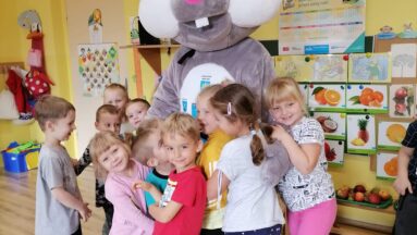 Grupa przedszkolaków przytula Kicaka w nowym futerku