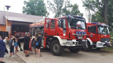 Dzieci i dorośli oglądający sprzęty wewnątrz wozu strażackiego