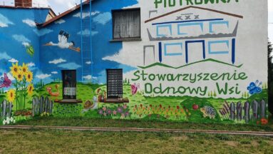 Mural kwiatowy wraz z logo Stowarzyszenia Odnowy Wsi Piotrówka.