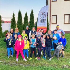 21 os&oacute;b rodzice z&nbsp;dziećmi na&nbsp;tle flagi Działaj Lokalnie